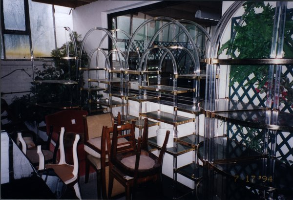 Groupe de chaises imbriquées devant trois meubles à étagère en plastique transparent.