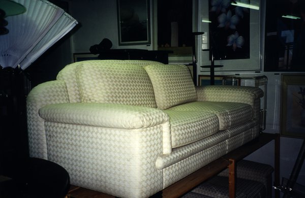 Sofa en tissu damassé blanc posé sur une table en bois.