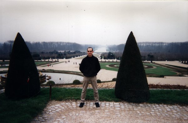 Homme debout devant le parc du château de Versailles.