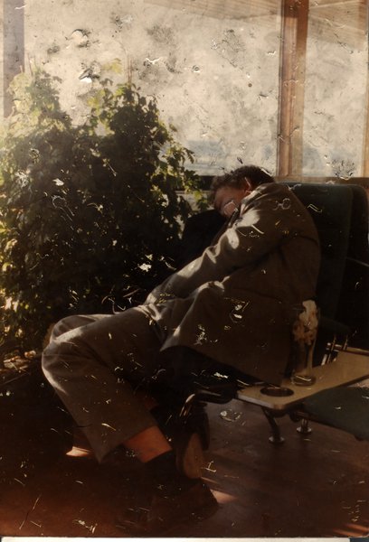 Homme endormi sur une chaise près d’une plante verte. Image avec marques de piqûres.