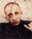 Jeune homme de face crâne dégarni et pull noir. Image avec biffures.