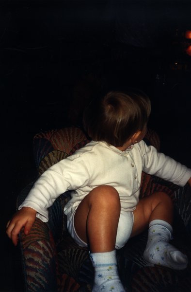 Enfant assis jambes nues avec gilet blanc.
