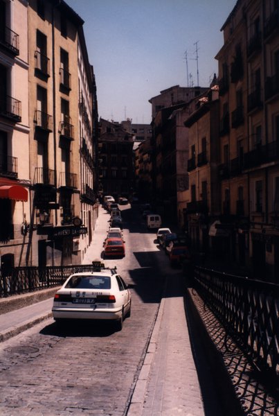 Rue pavée étroite bordée d'immeubles avec voitures garées.ᴬᴵ