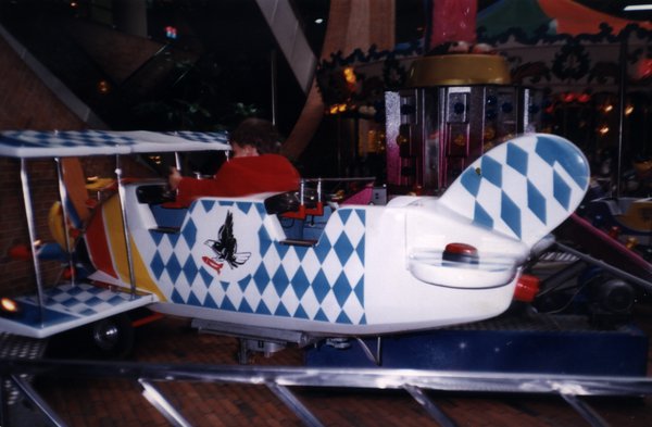 Manège en forme de biplan dans une fête foraine.ᴬᴵ