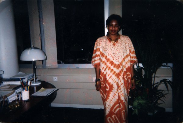 Femme en boubou de tissu batik debout près d’un bureau.