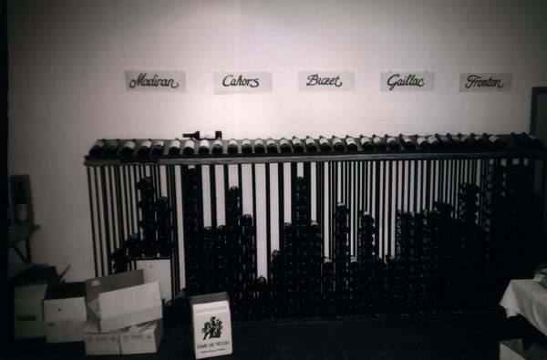 Rangement pour bouteilles de vin avec bouteilles et inscriptions murales aux noms des vins.