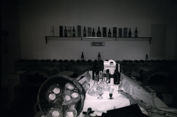 Table avec nappe blanche, carafes, et bouteilles dans un entrepot à vin.