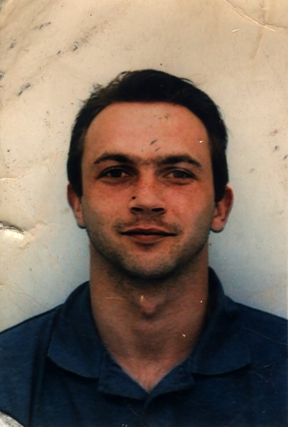 Homme brun de face en chemise sombre. Image abîmée.