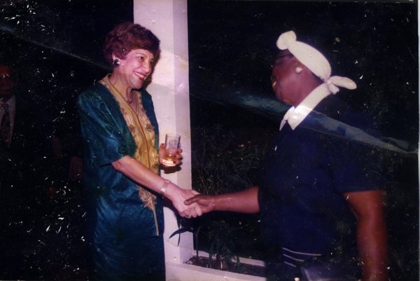 Femme souriante en train de serrer la main d’une femme corpulente avec un turban. Image avec pliure.