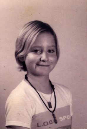 Petite fille blonde de trois quart en tee-shirt. Noir et blanc.