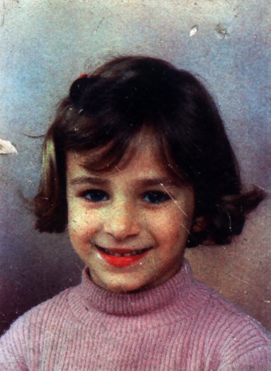 Visage de petite fille souriante à cheveux bruns et barrette.