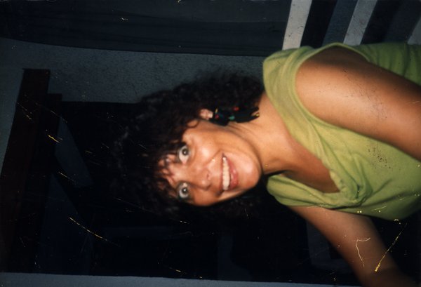 Femme brune le buste tourné de trois quart souriante, les yeux exorbités.