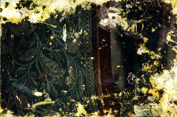 Pièce de bois recouverte d’un tissu vert à motifs. Image très abîmée.