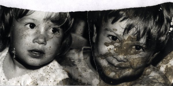 Gros plan de deux enfants au visage couvert de boue. Image avec déchirure, reconstituée. Noir et blanc.ᴬᴵ