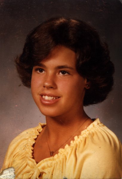 Visage de jeune fille brune souriante.