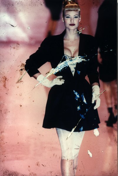 Mannequin sur un podium de défilé en robe fourreau et veste cintrée noire. Image avec rayures.