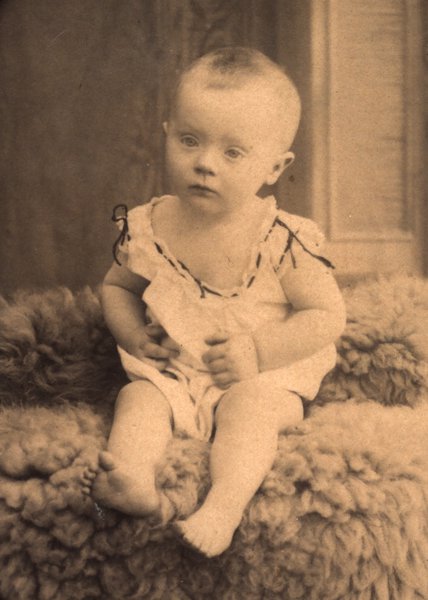 Portrait en studio d'un bébé assis sur une fourrure. Sépia.ᴬᴵ