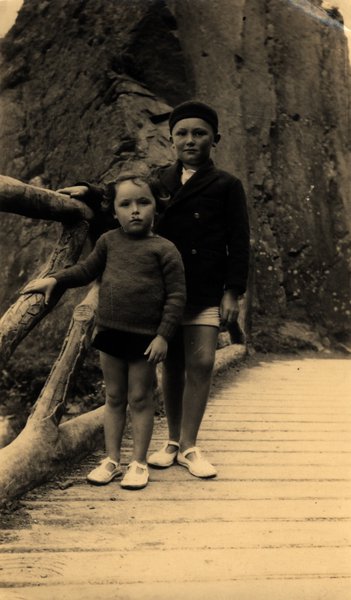 Deux enfants sur une passerelle en bois devant un rocher. Sépia.ᴬᴵ