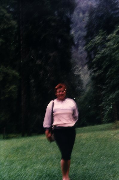 Femme marchant sur une pelouse devant des arbres. Image floue.ᴬᴵ