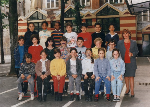 Élèves et leur professeur pose pour une photo de classe dans une cour d’école. Image avec traces de stylo.