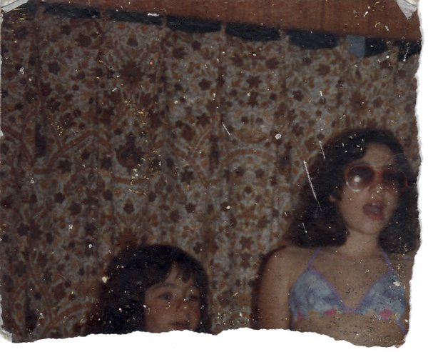 Jeune fille à lunettes de soleil et haut de maillot de bain devant un rideau à fleurs à ses côtés un enfant. Image déchirée.