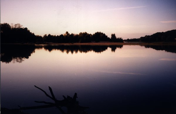 Crépuscule sur une étendue d’eau bordée de végétations.