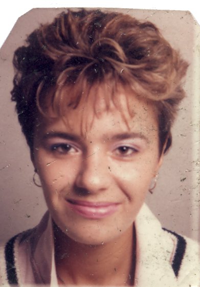 Visage souriant de femme à cheveux châtain clair  en veste noire et blanche.