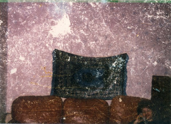 Grands coussins noirs et marron clair et femme brune au téléphone. Image très abîmée.