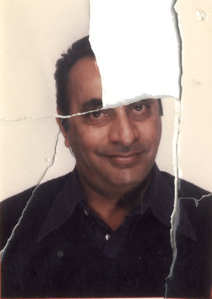 Visage souriant d’homme en chemise sombre. Image déchirée.