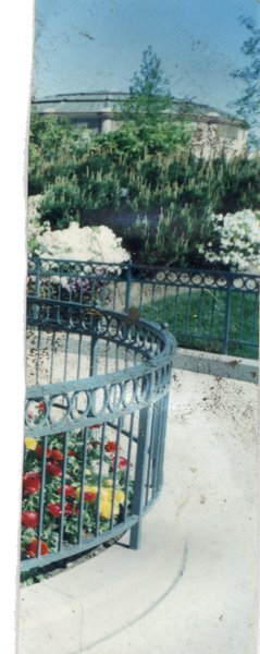 Jardin avec massifs de fleurs entourés de balustrades en métal.