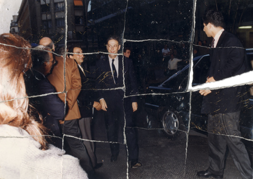 Hommes en costume et cravate et foule devant une voiture. Image déchirée reconstituée.