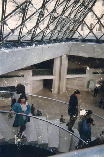 Personnes debout dans un escalier sous la pyramide du Louvre.