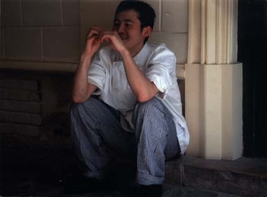 Homme accroupi devant un mur.