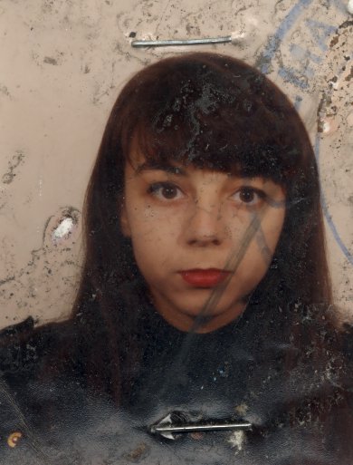 Visage de petite fille brune à frange. Image avec traces d’agrafes.