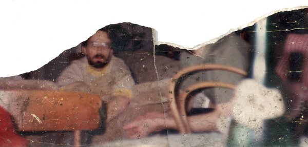 Hommes barbus à lunettes et chaise. Image déchirée en partie reconstituée.