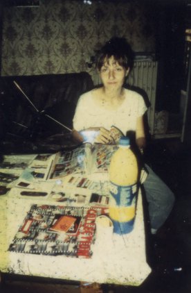Femme assise à une table et grande bouteille d’Orangina.