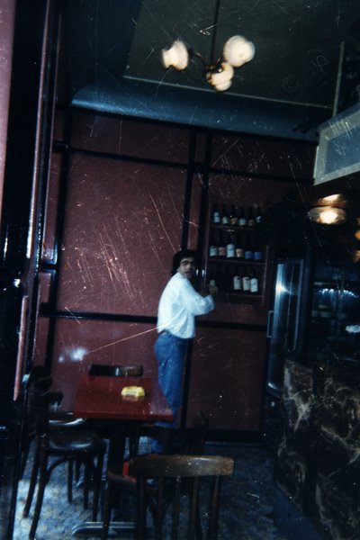 Homme debout dans un bar près d'une étagère de bouteilles. Image rayée.ᴬᴵ