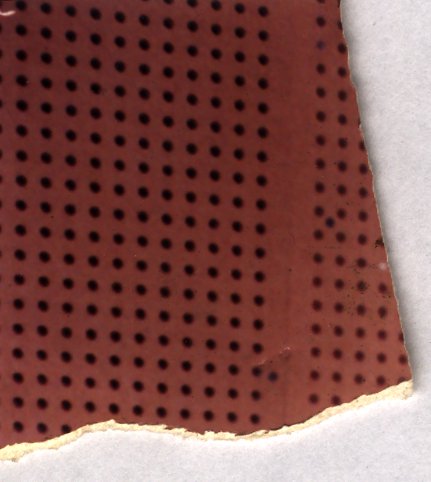 Gros plan sur une surface perforée brun-rouge.ᴬᴵ