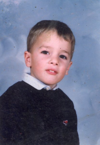 Visage de petit garçon blond en pull.