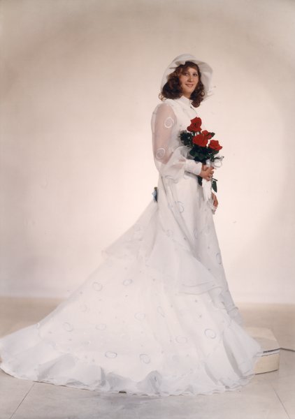 Mariée à chapeau blanc et bouquet de fleurs debout.