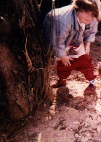 Petite fille accroupi contre un arbre pantalon baissé.
