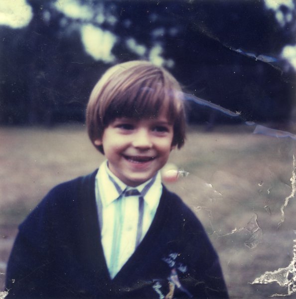 Buste de petit garçon blond à chemise rayée.