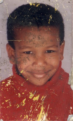 Portrait souriant d'un enfant en pull rouge, visage tacheté de peinture dorée.ᴬᴵ