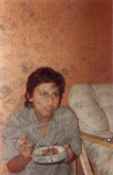 Femme brune assise, mange à la cuillère dans une assiette à large rebord.