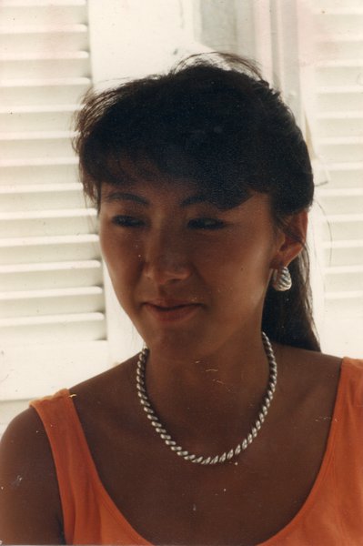 Visage de femme à queue-de-cheval avec un corsage orange et un collier.