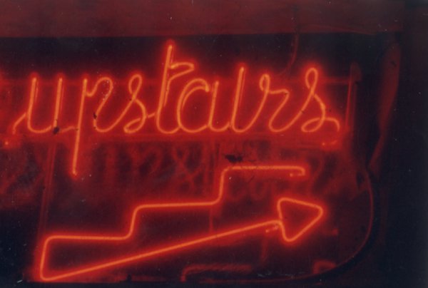 Inscription en néon rouge :  « Upstairs ».