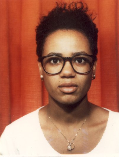 Visage de jeune femme avec lunettes à montures noires et corsage blanc.