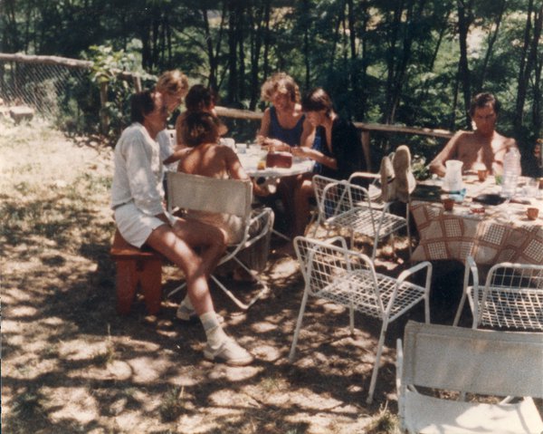 Hommes et femmes attablés sous des arbres en plein air.