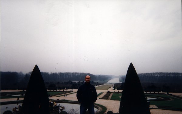 Homme barbu devant le parc du château de Versailles.