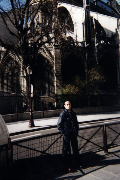 Homme accoudé à une balustrade devant la cathédrale Notre Dame de Paris.